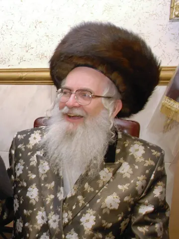 מוהרא״ש בשטריימל ובחליפת משי עם פרחים, מחייך